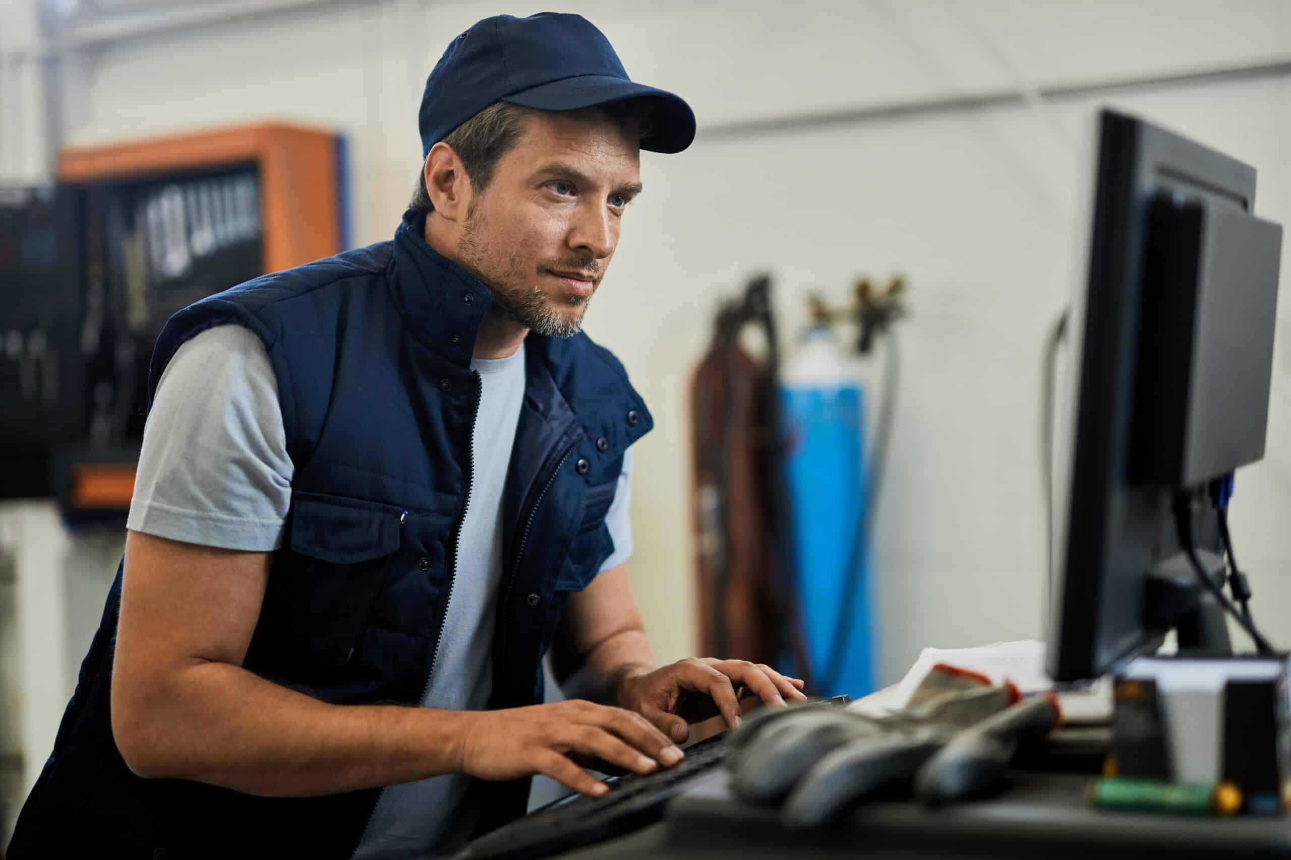 car mechanic using computer while working auto repair shop 1 scaled